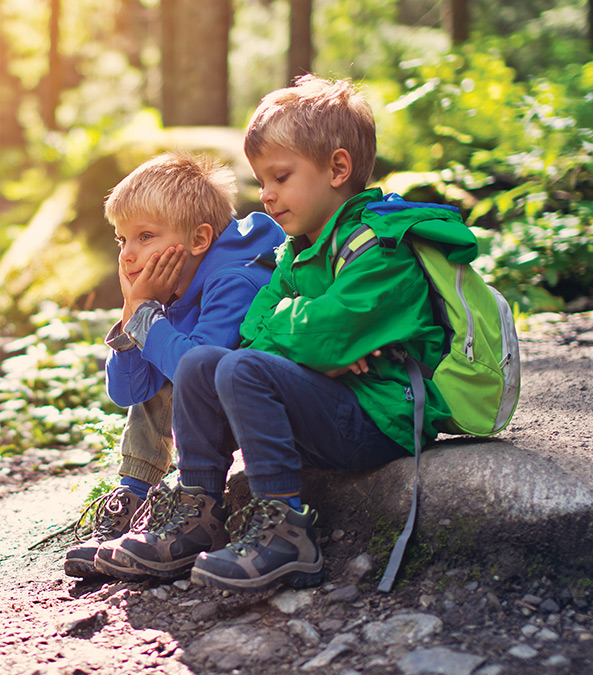 two little boys sitting in the woods